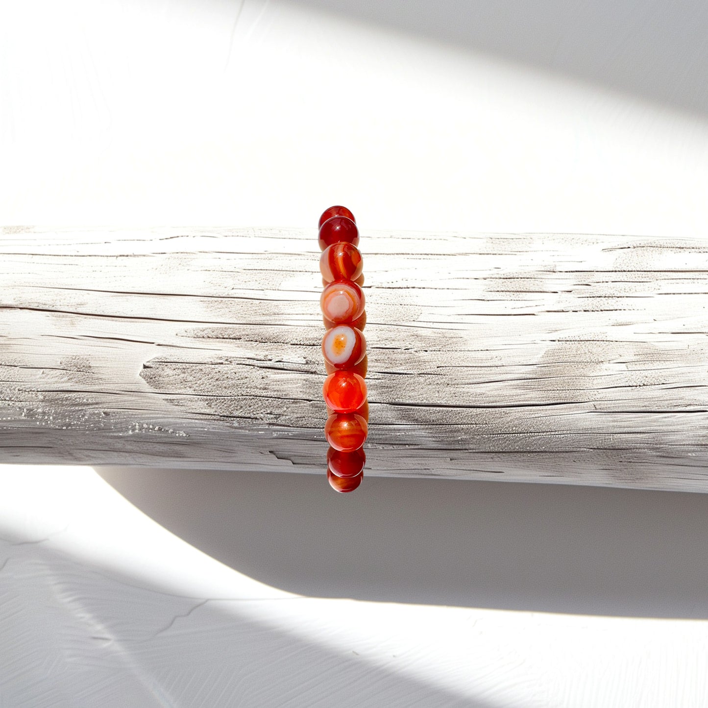 A carnelian bead bracelet crafted from smooth, vibrant beads, displayed on a bracelet stand. Known for manifesting courage, confidence, and creativity, this bracelet harnesses the dynamic energy of carnelian to inspire a renewed sense of purpose and ambition. Its vibrant vibrations boost confidence, ignite creativity, and fuel passion, empowering the wearer to overcome obstacles and achieve goals with grace and ease. Ideal for those seeking support on their journey to success and self-discovery.