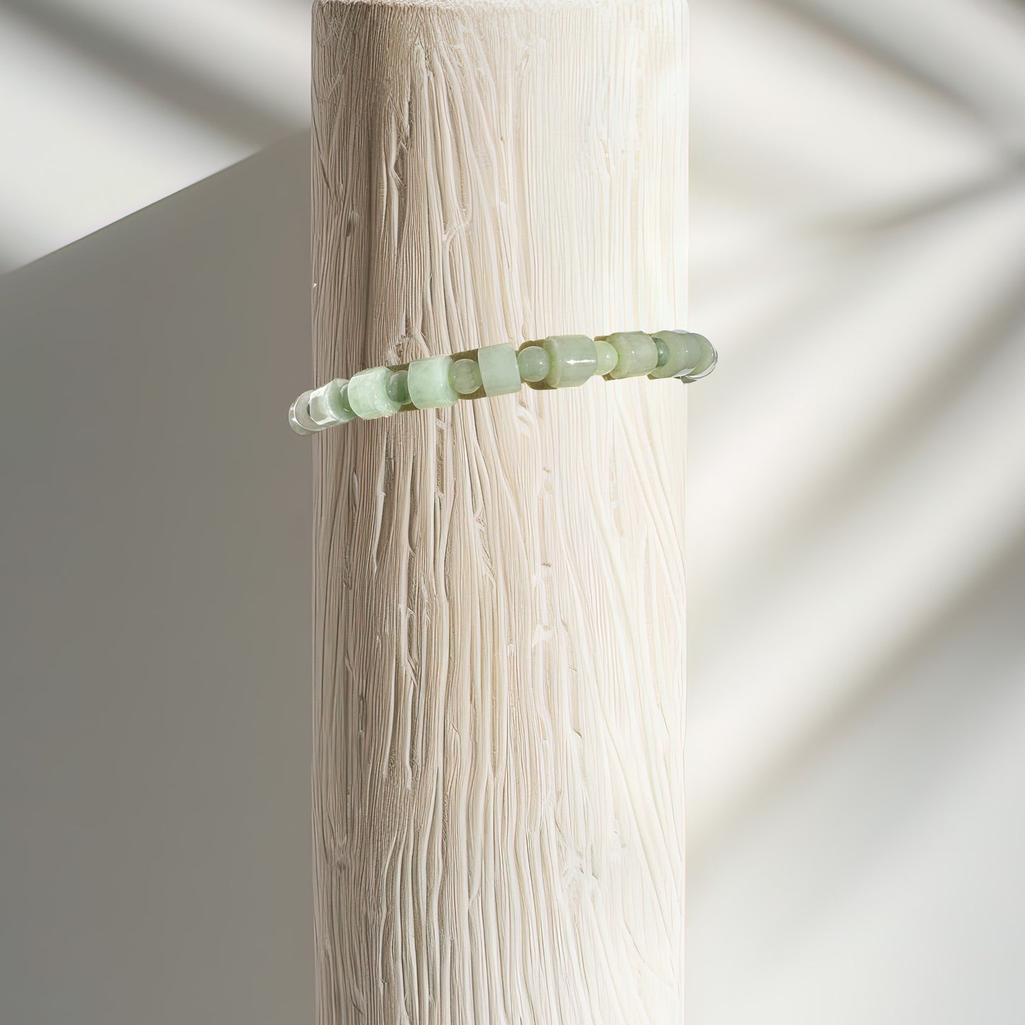 A jade bracelet crafted from a blend of square and round beads, displayed on a bracelet stand. The square beads symbolize stability, grounding, and protection, while the round beads represent unity, wholeness, and the infinite cycles of life. This combination creates a powerful synergy that enhances the bracelet's energy, promoting balance, harmony, and spiritual growth.